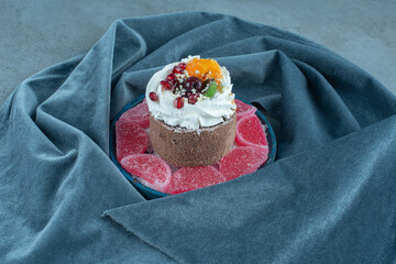 Small cake and marmelades on a platter on marble background
