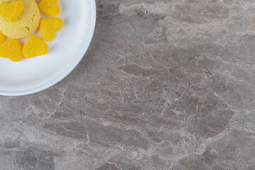 Heart marmelades surrounding a cookie on a platter on marble background