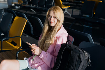 A young woman while waiting for a plane at the airport. A traveler with a mobile phone.