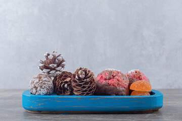 Cookies and pine cones on a blue platter on marble background