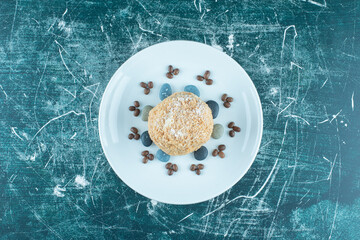 Squirrel cake on a platter with candy rocks and coffee beans on blue background