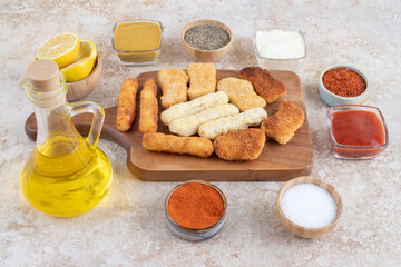 Grilled sausages, cheese sticks and chicken nuggets with sauces on a wooden platter