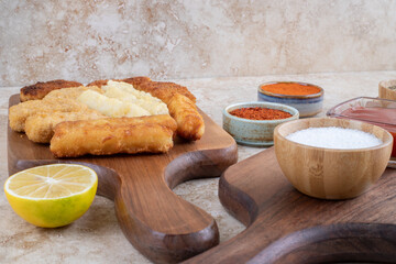 Classic chicken nuggets, sausage and cheese sticks on a wooden platter