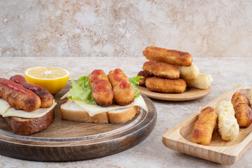 Grilled sausage and chicken nuggets on sandwich toastes with herbs and spices on a wooden platter