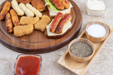 Grilled sausages, cheese sticks and chicken nuggets with sauces on a wooden platter