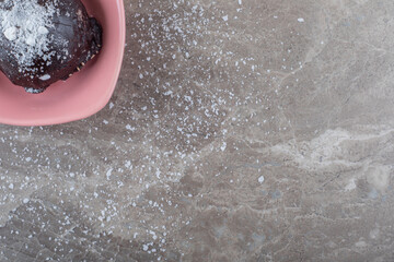 Small, chocolate coated cake in a bowl on marble background