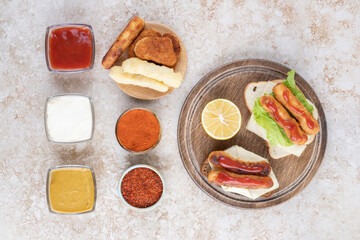 Cheese stiks and grilled sausages on a slice of toast bread with variety of sauces aside