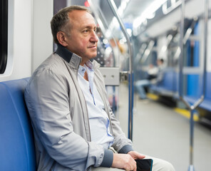 Positive elderly man sitting in an empty subway carriage while train is moving