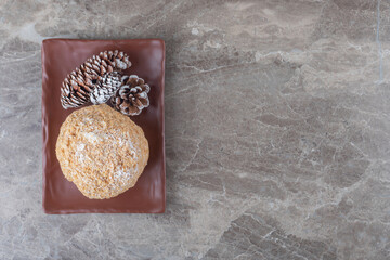 Squirrel cake and pines cones on a brown platter on marble background