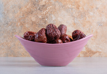 Dry red jujube berries in a purple bowl