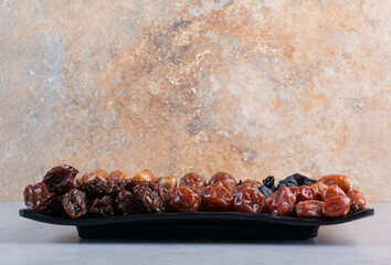Selection of dry fruits on a platter on concrete background