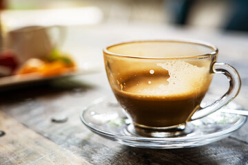 Half cup of coffee in clear cup on old wooden desk , dark tone