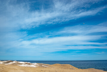 Fototapeta na wymiar Endless azure sky with white clouds, sandy shore, beach. Calm inspiring sea view.