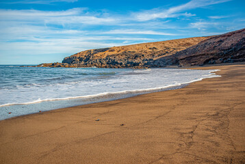 Fototapeta na wymiar White sea foam, sandy shore, pebbles on a sandy beach. Calm inspiring sea view.