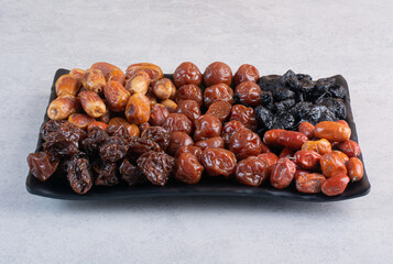 Dry fruit combination on a platter on concrete background