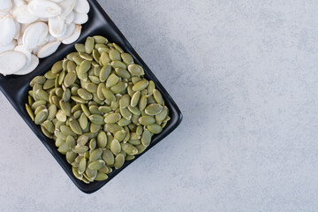 Green cleaned and white pumpkin seeds on concrete background