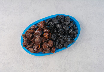 Dried black cherry and plums in a blue platter