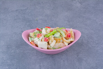 Salad with chopped vegetables and herbs on blue background