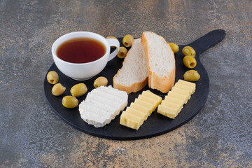 Black breakfast board with bread and a cup of tea