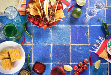 Traditional Mexican corn tacos with meat, vegetables, avocado, beans, salsa and nachos. Served with various sauces and drinks. Top view. Big family gatherings.