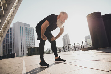 Photo of tired exhausted sportive pensioner man take break catch heavy breath sunset training urban town outdoors