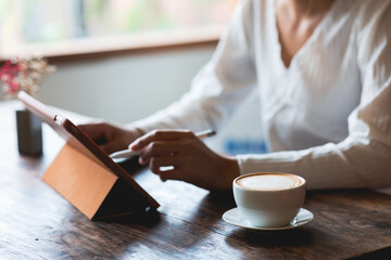Coffee cup. Woman using tablet to work in cafe shop. vintage wooden table