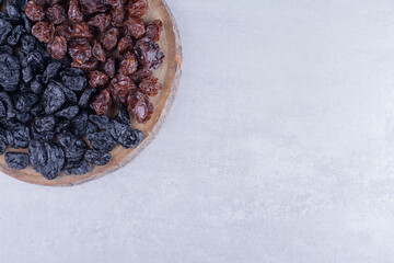 Black dry plums isolated on a wooden platter