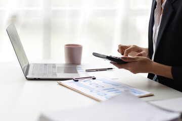Business woman working on laptop and financial documents, female accountant in the office analyzes the budget using a calculator.