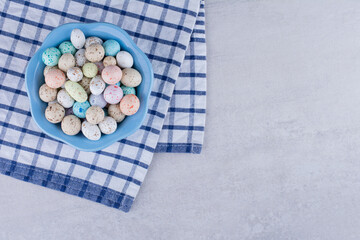 Colorful stone candies in a plate on concrete background