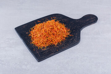Saffron seeds on a wooden platter on concrete background