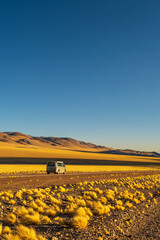 Campervan in a black dirty road with yellow grass in La Puna Argentina