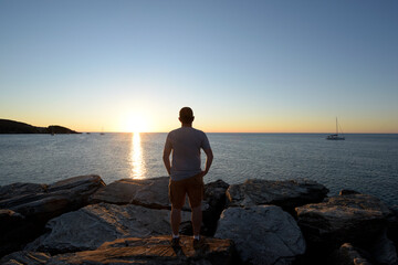 silhouette d'un homme en train de regarder le coucher de soleil sur les rochers - Méditerranée