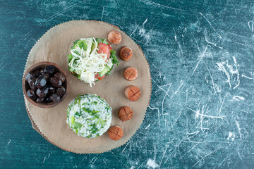 Snack board with salad and sausages on blue background