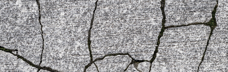 Old grey granite tiles are laid on the streets of the city. Banner of cracked granite tiles