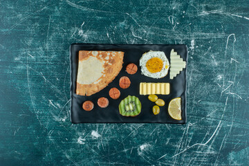 Breakfast menu on a wooden board with eggs, crepes and side foods