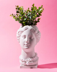 Trendy Venus plaster head planter pot with pearls jewelry on pink background. Neon colors