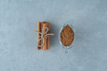 Cinnamon sticks and powder in a glass cup