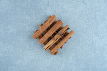Cinnamon sticks in a pile on blue background