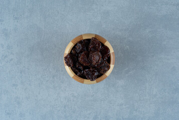 Fototapeta na wymiar Dried sour cherries in a wooden cup on blue background