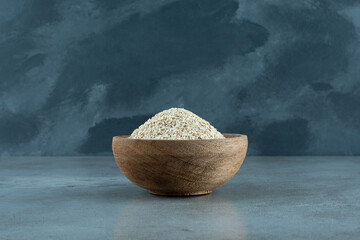 Wheat or rice grains in a wooden cup on blue background