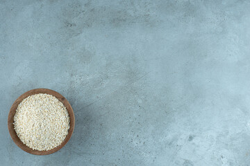 Wheat or rice grains in a wooden cup on blue background