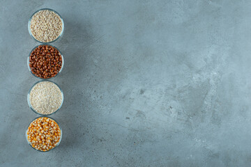 Variety of seeds in glass cups on blue background