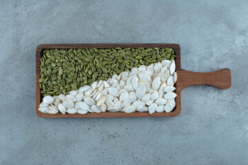 Green and white pumpkin seeds on blue background