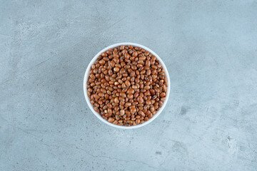 Dry brown beans in a white ceramic cup