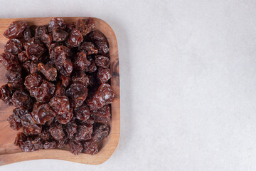 Fototapeta na wymiar Dried brown plums on a wooden platter