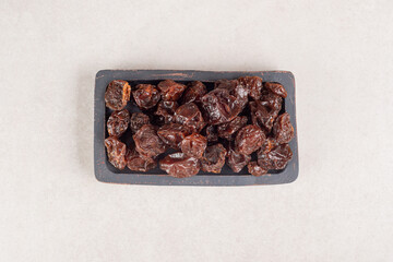 Dried brown plums on a wooden platter