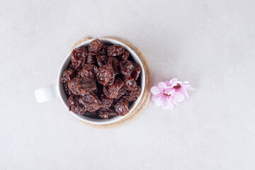 Fototapeta na wymiar Dried brown plums in a ceramic cup or bowl