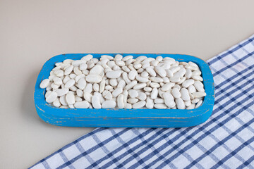 White beans on a piece of board on concrete background