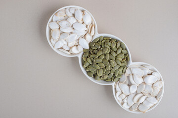 White and green pumpkin seeds in white cups