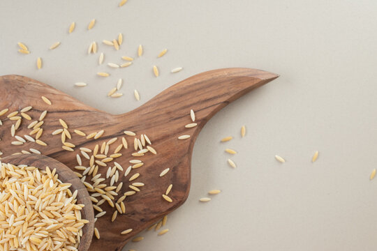 Yellow rice seeds in a wooden rustic cup on concrete background